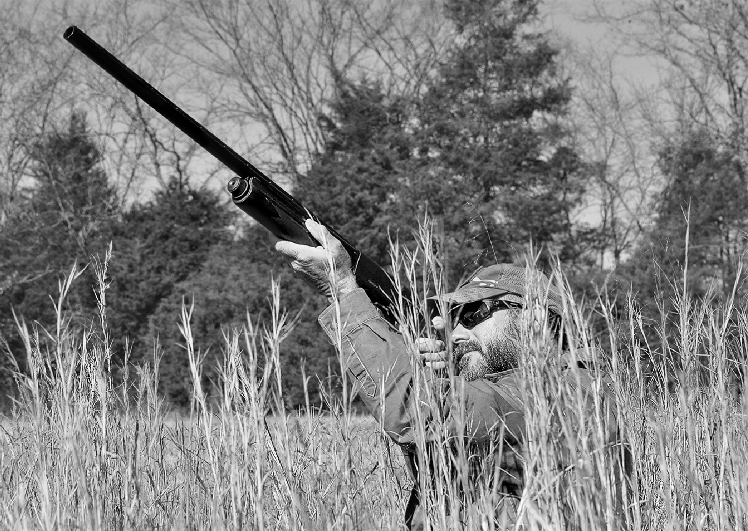 A man in a field shooting a rifle