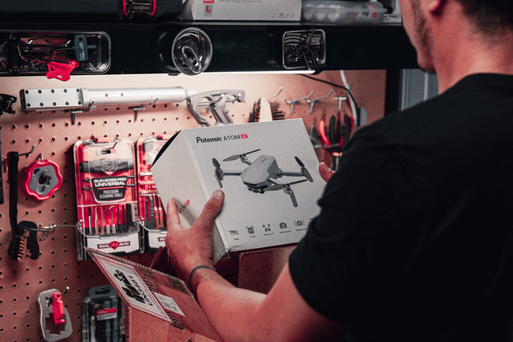 A man holding a box containing a drone